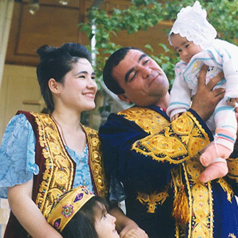 Uzbek family, a woman holding a child's arm and a man holding a baby in his arms.